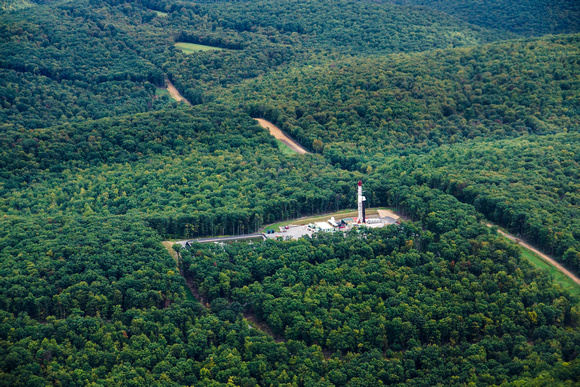 Road and parallel pipeline, drilling rig and impoundment cut through the forest near State Game Lands 114 north of Jersey Shore, PA.
