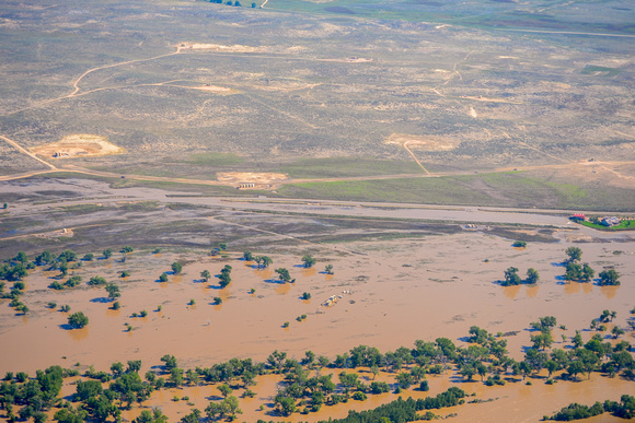 Numerous completed wellpads: Wellheads, crude oil tanks, toxic waste water tanks, separators, combustor flares submerged under flood waters along the South Platte River, Colorado